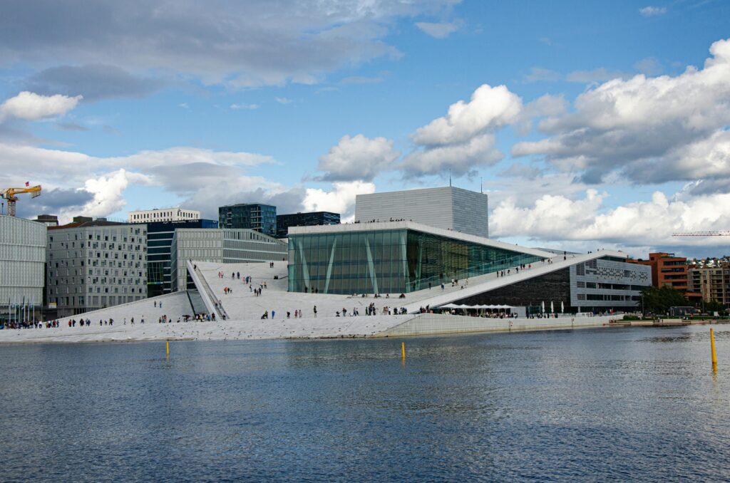 Stunning view of the Oslo Opera House by the waterfront under a blue sky, showcasing modern architecture.