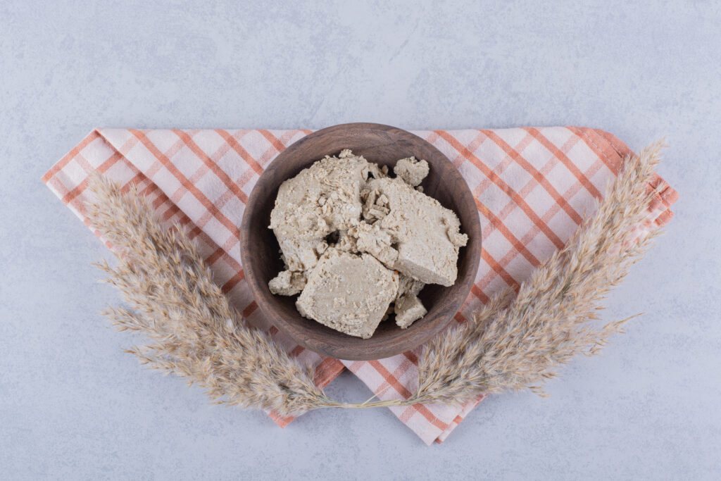 A close-up of a standard block of fresh compressed yeast (Lievito di Birra). This living, moist yeast is the traditional choice for authentic Neapolitan pizza, starting fermentation instantly and providing a clean, floral aroma to the slow-rising dough.